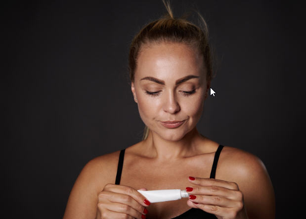 A middle-aged woman calmly holding a cream tube, symbolizing the use of bioidentical hormone therapy and self-care during menopause.