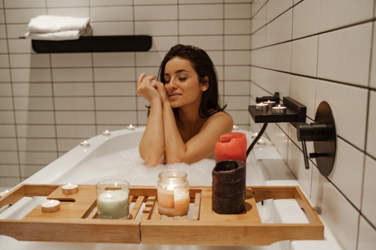 Woman standing in a clean bathroom surrounded by multiple personal care products, illustrating excessive hygiene and its effect on sensitive skin